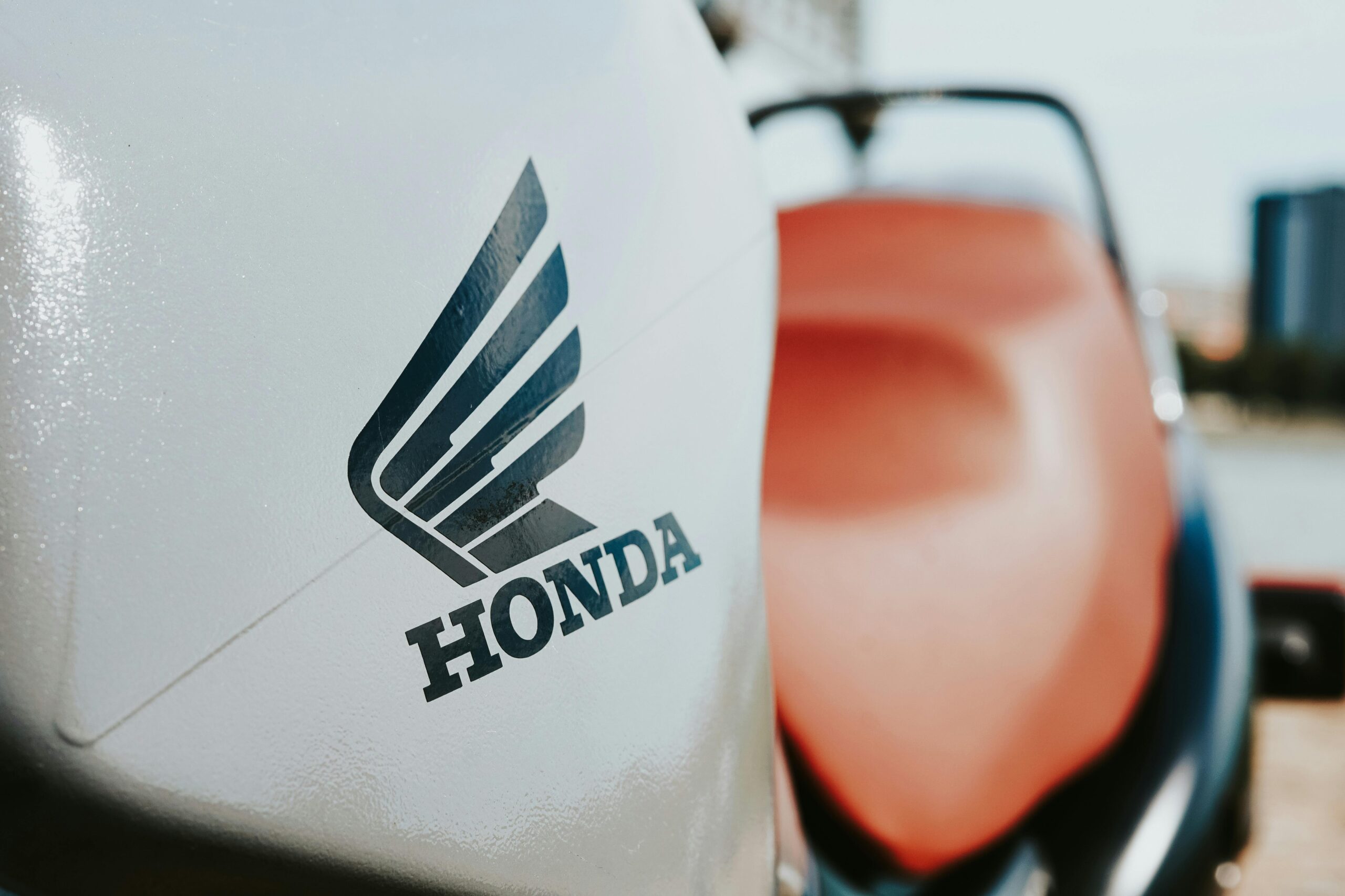 Detailed view of a Honda motorcycle logo on a sleek vehicle surface.